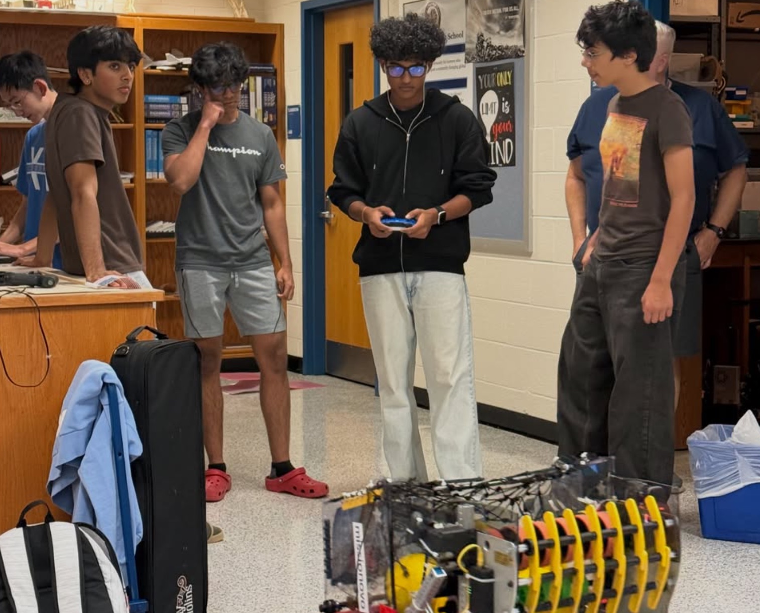 A student drives a competition robot with a controller while teammates watch